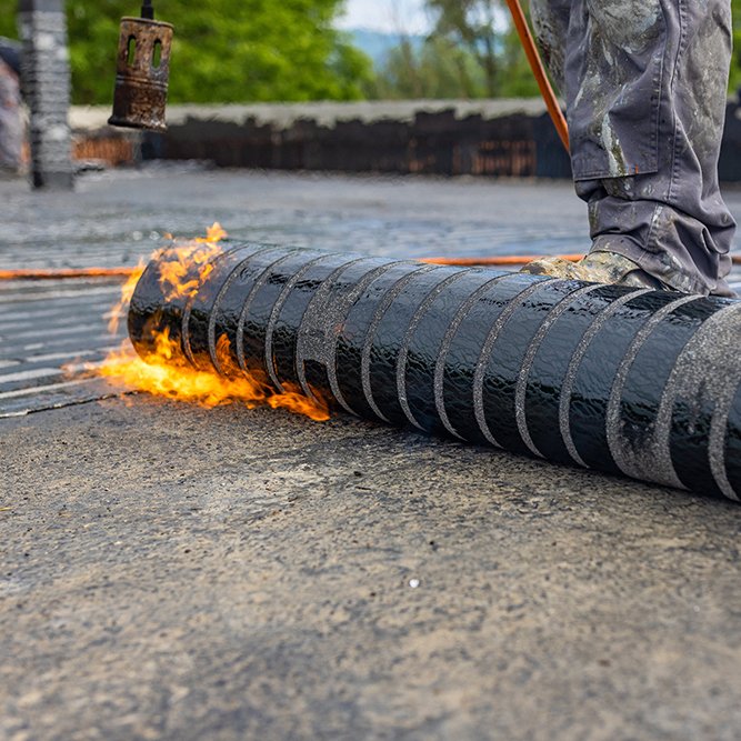 Workers placing a vapor barrier on the roof using a propane gas