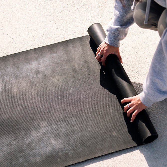 hands of a young woman rolling a yoga mat