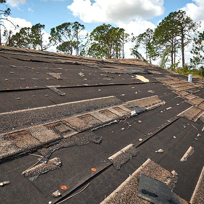 Damaged house roof with missing shingles after hurricane Ian in Florida. Consequences of natural disaster
