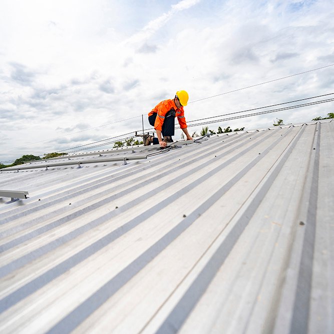 Technician in safety uniform and helmet kneeling on a rooftop, u